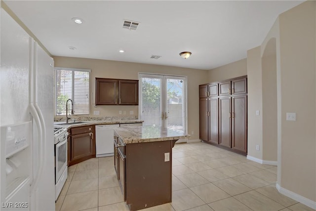 kitchen with white appliances, a sink, healthy amount of natural light, a center island, and recessed lighting