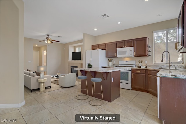 kitchen featuring white appliances, a center island, open floor plan, a kitchen breakfast bar, and a sink