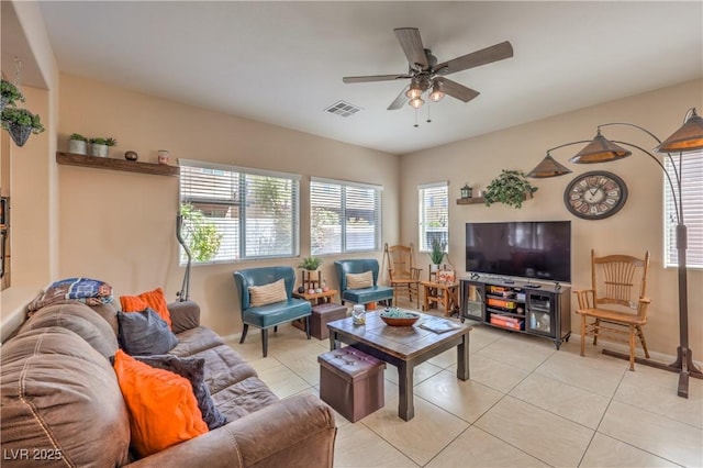 living area with a ceiling fan, plenty of natural light, light tile patterned floors, and baseboards