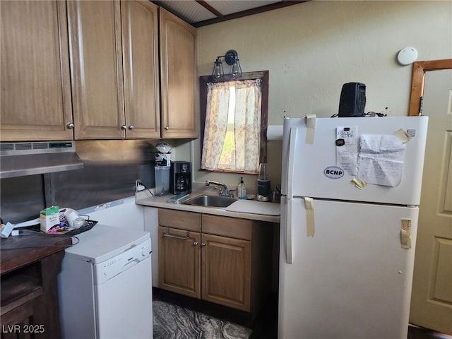 kitchen featuring freestanding refrigerator, a sink, light countertops, refrigerator, and brown cabinets