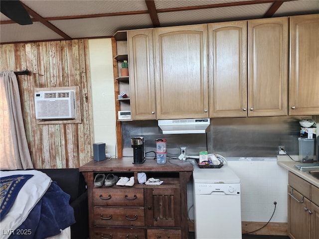 kitchen featuring light brown cabinetry, a wall mounted air conditioner, under cabinet range hood, wooden walls, and light countertops