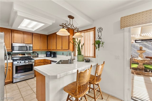 9522 Arrowhead Falls Ct, Las Vegas, NV 89148 - kitchen featuring stainless steel appliances, a sink, light tile patterned floors, a peninsula, and brown cabinetry