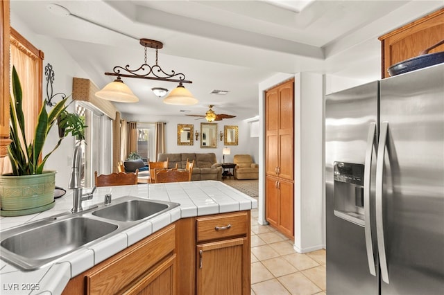9522 Arrowhead Falls Ct, Las Vegas, NV 89148 - kitchen with stainless steel refrigerator with ice dispenser, light tile patterned floors, open floor plan, a sink, and hanging light fixtures