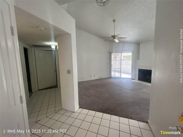 6512 Sterling Springs Pkwy, Las Vegas, NV 89108 - unfurnished living room with a textured ceiling, light carpet, a ceiling fan, light tile patterned floors, and a fireplace