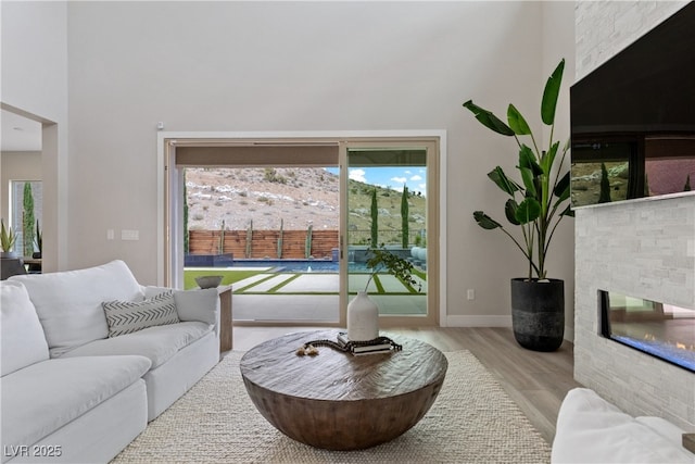 2601 Nevada Agave Ln, Las Vegas, NV 89138 - living room featuring a high ceiling, wood finished floors, a stone fireplace, and baseboards
