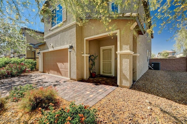 8164 Golden Cholla Ave, Las Vegas, NV 89179 - property entrance featuring an attached garage, stucco siding, central AC unit, fence, and driveway