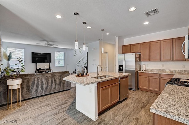 8164 Golden Cholla Ave, Las Vegas, NV 89179 - kitchen with a sink, stainless steel appliances, open floor plan, ceiling fan, and brown cabinets