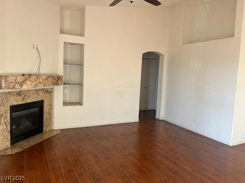 6201 E Lake Mead Blvd Unit 218, Las Vegas, NV 89156 - unfurnished living room with ceiling fan, arched walkways, wood-type flooring, a fireplace, and baseboards