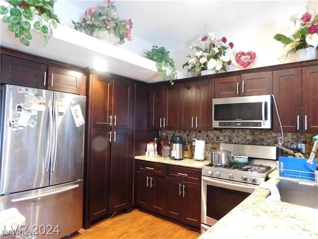 6201 E Lake Mead Blvd Unit 218, Las Vegas, NV 89156 - kitchen with stainless steel appliances, light wood-type flooring, decorative backsplash, light stone countertops, and a sink