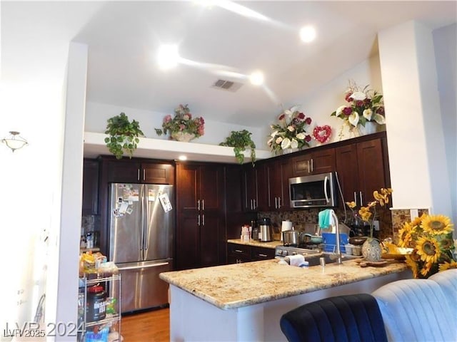 6201 E Lake Mead Blvd Unit 218, Las Vegas, NV 89156 - kitchen with appliances with stainless steel finishes, a peninsula, light stone countertops, tasteful backsplash, and a breakfast bar