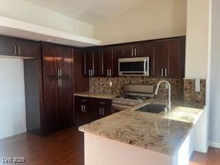 6201 E Lake Mead Blvd Unit 218, Las Vegas, NV 89156 - kitchen featuring appliances with stainless steel finishes, a peninsula, dark brown cabinetry, and tasteful backsplash