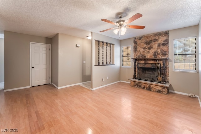 1729 Yellow Rose St, Las Vegas, NV 89108 - unfurnished living room featuring a textured ceiling, a ceiling fan, light wood finished floors, a fireplace, and baseboards