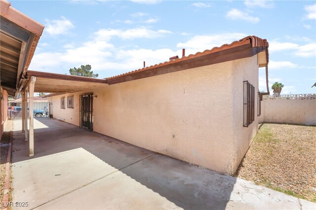 1729 Yellow Rose St, Las Vegas, NV 89108 - view of side of home featuring stucco siding, fence, a carport, and a tiled roof