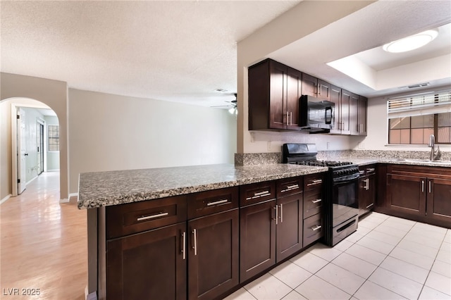 1729 Yellow Rose St, Las Vegas, NV 89108 - kitchen featuring black appliances, a sink, arched walkways, a ceiling fan, and a peninsula