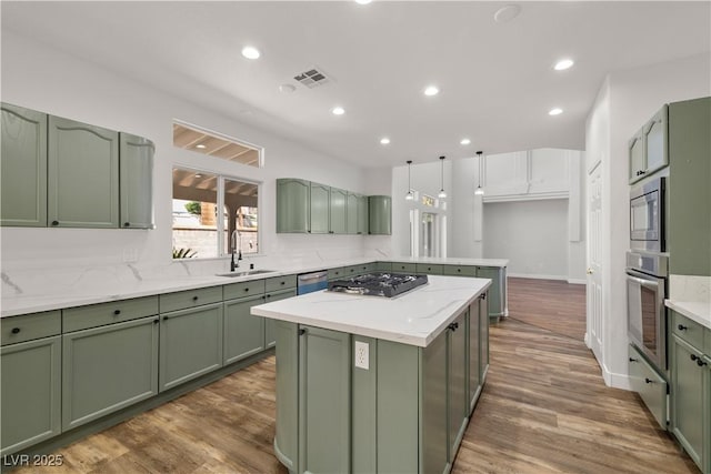 4607 El Camino Cabos Dr, Las Vegas, NV 89147 - kitchen with green cabinets, appliances with stainless steel finishes, a sink, a kitchen island, and a peninsula