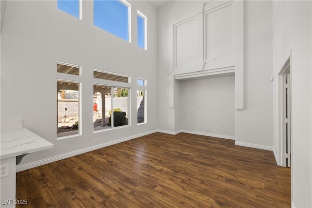 4607 El Camino Cabos Dr, Las Vegas, NV 89147 - unfurnished living room with dark wood-style floors, a high ceiling, and baseboards