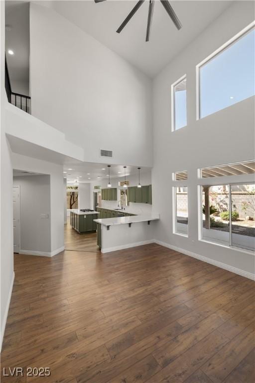 4607 El Camino Cabos Dr, Las Vegas, NV 89147 - unfurnished living room featuring a towering ceiling, a ceiling fan, baseboards, and dark wood-type flooring