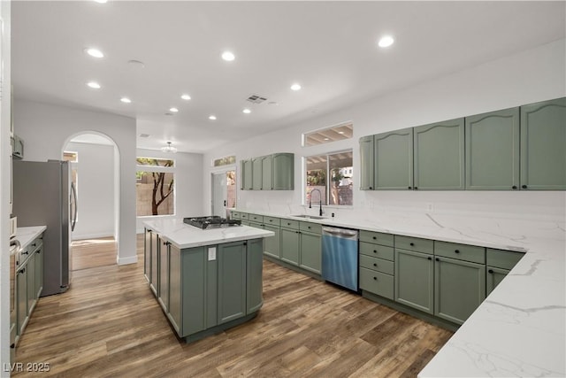 4607 El Camino Cabos Dr, Las Vegas, NV 89147 - kitchen featuring green cabinets, stainless steel appliances, a center island, a sink, and arched walkways