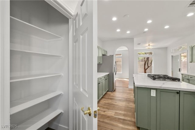 4607 El Camino Cabos Dr, Las Vegas, NV 89147 - kitchen featuring green cabinets, stainless steel appliances, recessed lighting, light wood-type flooring, and arched walkways