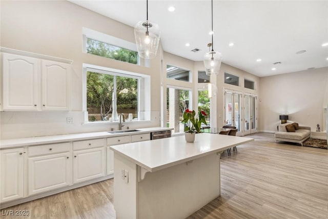 801 Aquitaine Ct, Las Vegas, NV 89145 - kitchen featuring open floor plan, stainless steel dishwasher, decorative light fixtures, a kitchen island, and light wood-style flooring