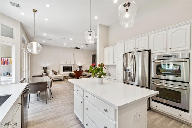801 Aquitaine Ct, Las Vegas, NV 89145 - kitchen featuring appliances with stainless steel finishes, white cabinets, light wood-type flooring, light countertops, and hanging light fixtures