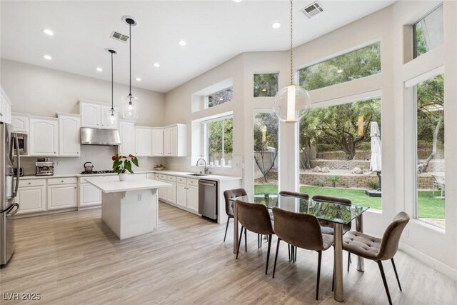 801 Aquitaine Ct, Las Vegas, NV 89145 - kitchen featuring a towering ceiling, appliances with stainless steel finishes, under cabinet range hood, white cabinetry, and a center island