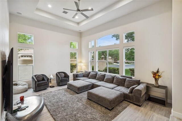 801 Aquitaine Ct, Las Vegas, NV 89145 - living room featuring healthy amount of natural light, wood finished floors, a ceiling fan, a tray ceiling, and a towering ceiling