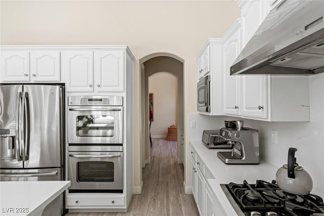 801 Aquitaine Ct, Las Vegas, NV 89145 - kitchen featuring range hood, stainless steel appliances, arched walkways, and white cabinetry