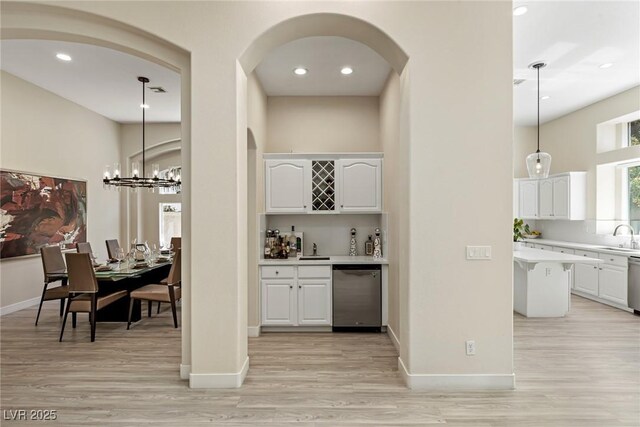801 Aquitaine Ct, Las Vegas, NV 89145 - indoor bar with dishwashing machine, light wood-type flooring, arched walkways, a high ceiling, and hanging light fixtures