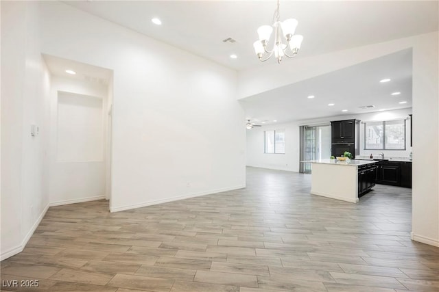 unfurnished living room with a chandelier, light wood-type flooring, recessed lighting, and baseboards