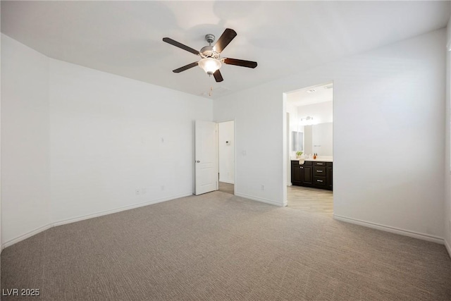 unfurnished bedroom featuring light carpet, baseboards, ensuite bathroom, and a ceiling fan