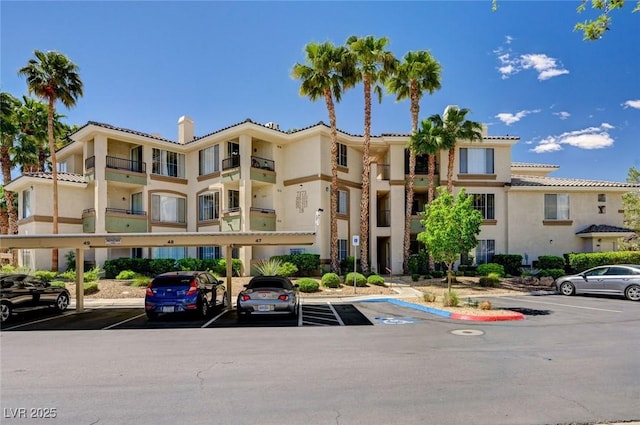 view of property featuring covered and uncovered parking