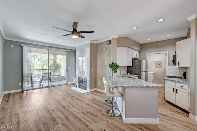 kitchen with a sink, stainless steel appliances, baseboards, white cabinets, and crown molding
