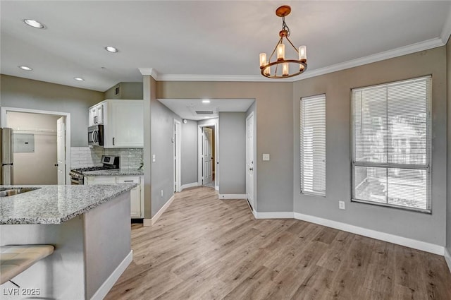 kitchen featuring stainless steel appliances, white cabinetry, light wood-type flooring, baseboards, and crown molding