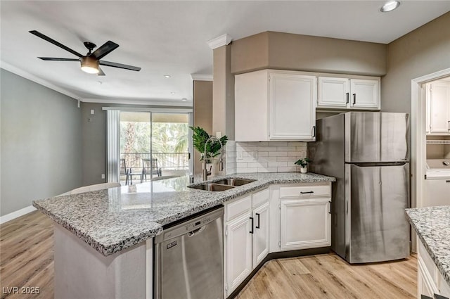 kitchen featuring appliances with stainless steel finishes, a peninsula, white cabinetry, light wood finished floors, and backsplash