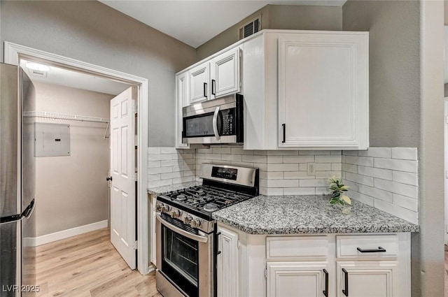 kitchen with stainless steel appliances, light wood-style flooring, white cabinetry, baseboards, and light stone countertops