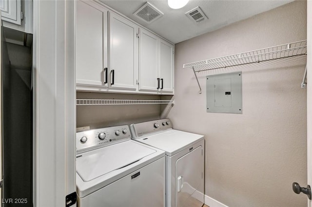 washroom with electric panel, washer and dryer, cabinet space, and baseboards