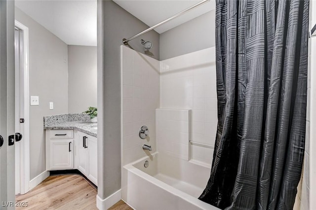 bathroom featuring wood finished floors, shower / bath combo with shower curtain, baseboards, and vanity