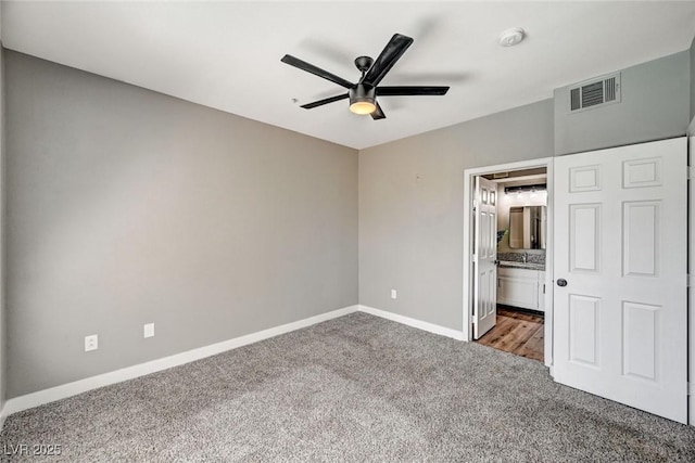 unfurnished bedroom with carpet flooring, baseboards, ensuite bathroom, ceiling fan, and a sink