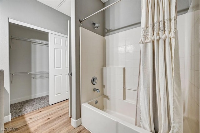 bathroom featuring wood finished floors, shower / tub combo, and baseboards