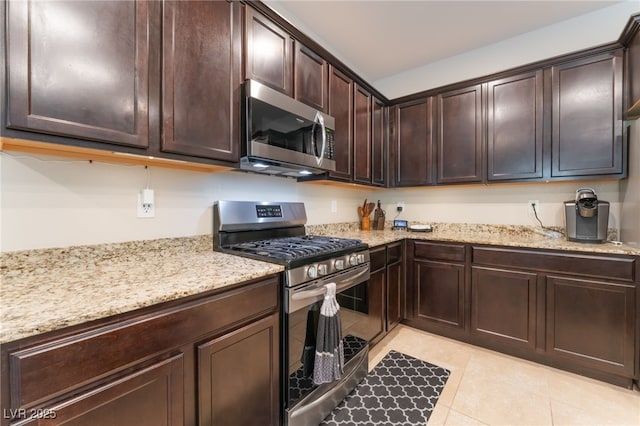 4524 Stardusk Falls Ave, North Las Vegas, NV 89084 - kitchen with stainless steel appliances, light stone countertops, dark brown cabinets, and light tile patterned flooring