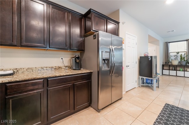4524 Stardusk Falls Ave, North Las Vegas, NV 89084 - kitchen with stainless steel fridge, dark brown cabinets, light tile patterned floors, and light stone counters