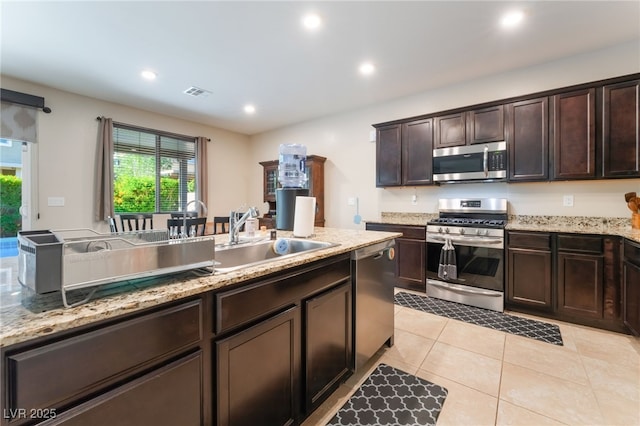 4524 Stardusk Falls Ave, North Las Vegas, NV 89084 - kitchen with stainless steel appliances, healthy amount of natural light, dark brown cabinetry, light tile patterned flooring, and recessed lighting