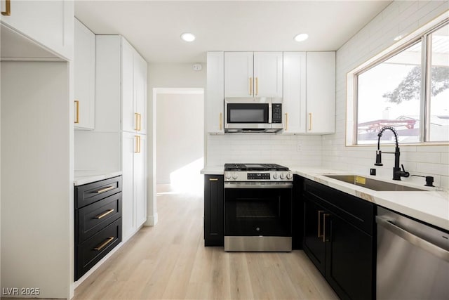 4669 Winfield Dr, Las Vegas, NV 89147 - kitchen with stainless steel appliances, a sink, dark cabinets, white cabinetry, and decorative backsplash