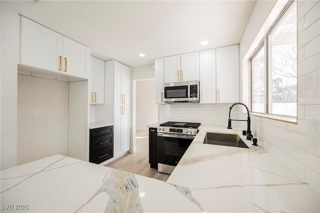 4669 Winfield Dr, Las Vegas, NV 89147 - kitchen with stainless steel appliances, a sink, decorative backsplash, white cabinets, and light stone countertops