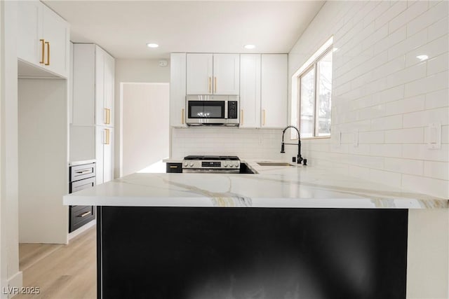 4669 Winfield Dr, Las Vegas, NV 89147 - kitchen with stainless steel appliances, a sink, decorative backsplash, a peninsula, and light wood-type flooring