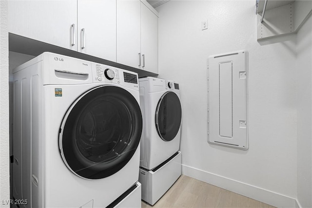 laundry room featuring washer and dryer, cabinet space, light wood-style floors, and baseboards