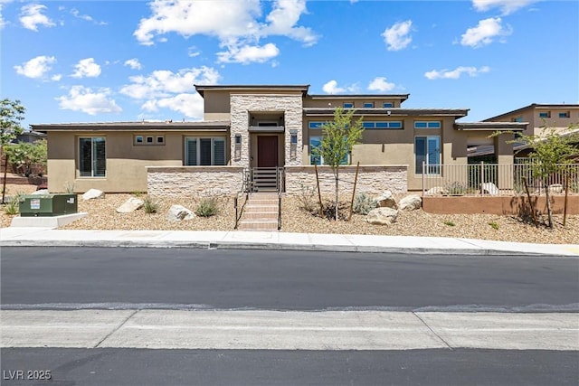 prairie-style home featuring stone siding, stucco siding, and fence