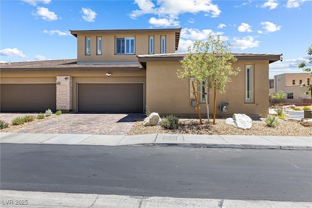 view of front of home with decorative driveway, stucco siding, and an attached garage
