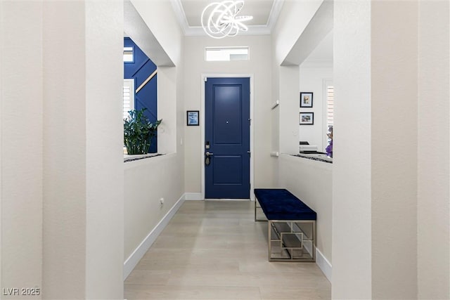 foyer featuring crown molding, a chandelier, light wood-style floors, baseboards, and a high ceiling
